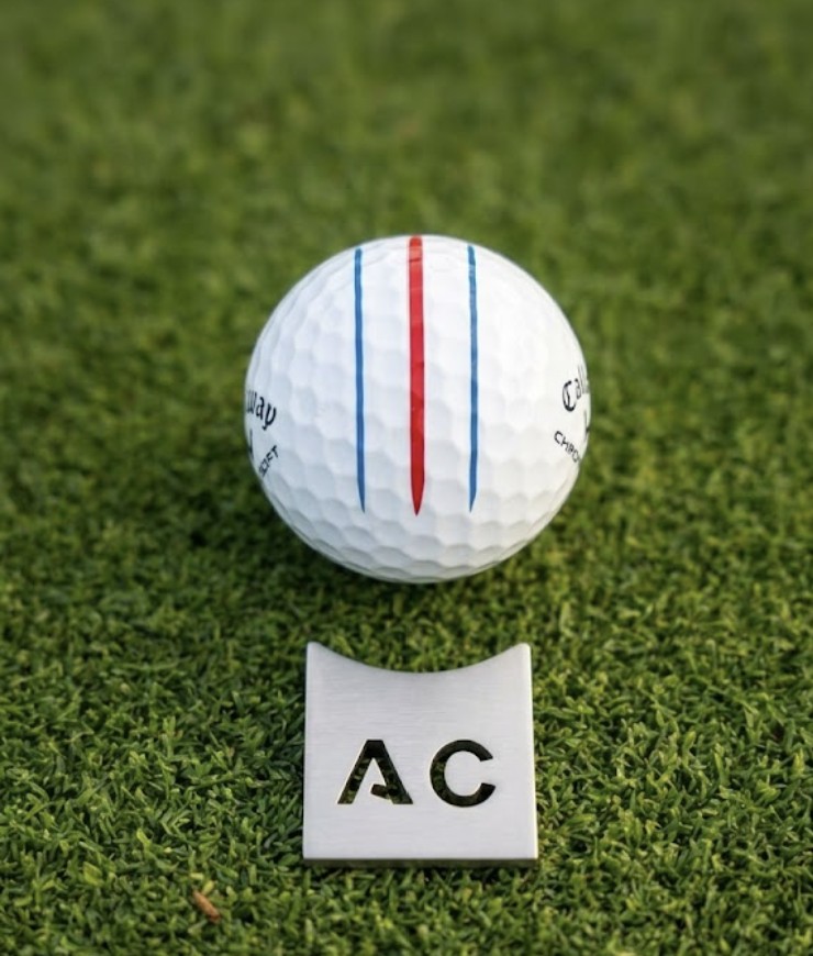 Bola de golf junto a marcador personalizado con iniciales AC
